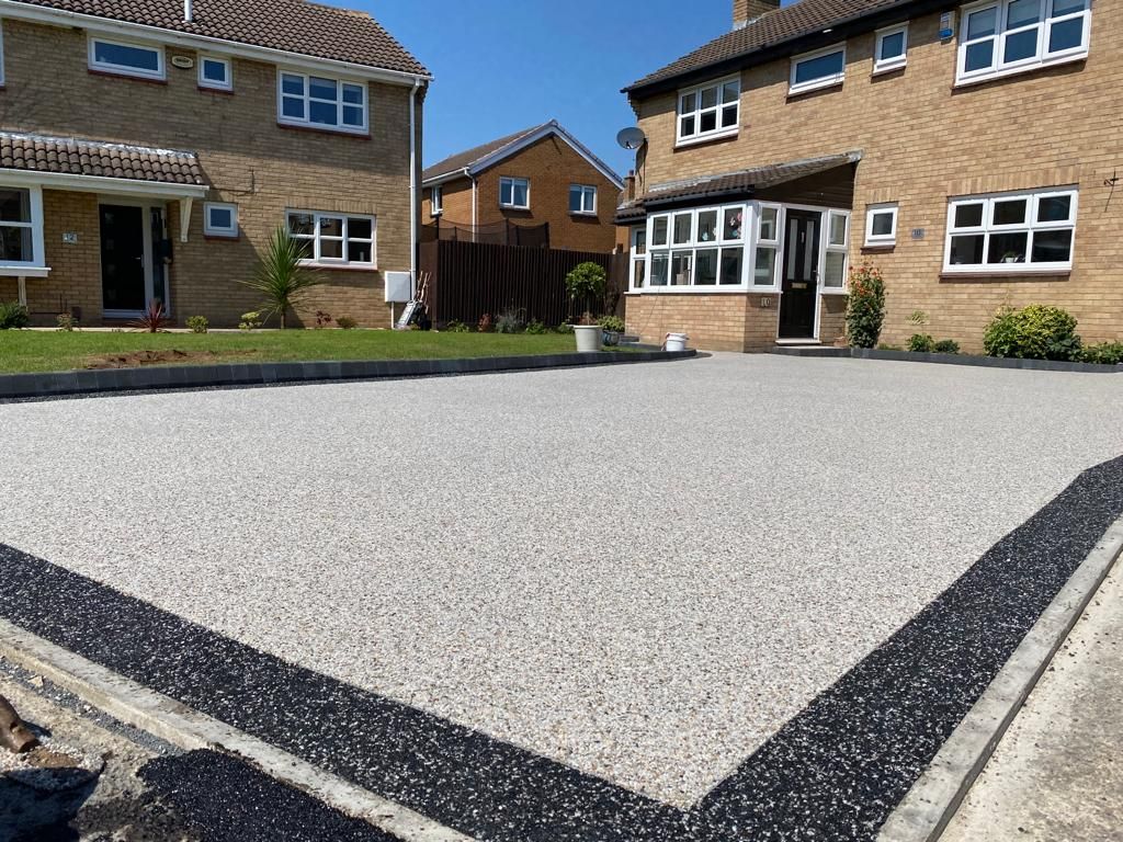 Silver resin bound driveway with a black perimeter band, laid seamlessly from kerb to door