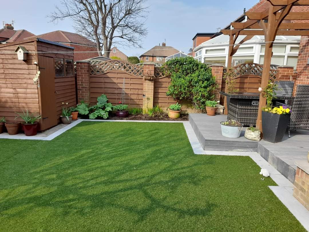 Porcelain paving, artificial lawn and raised decking in a rear garden