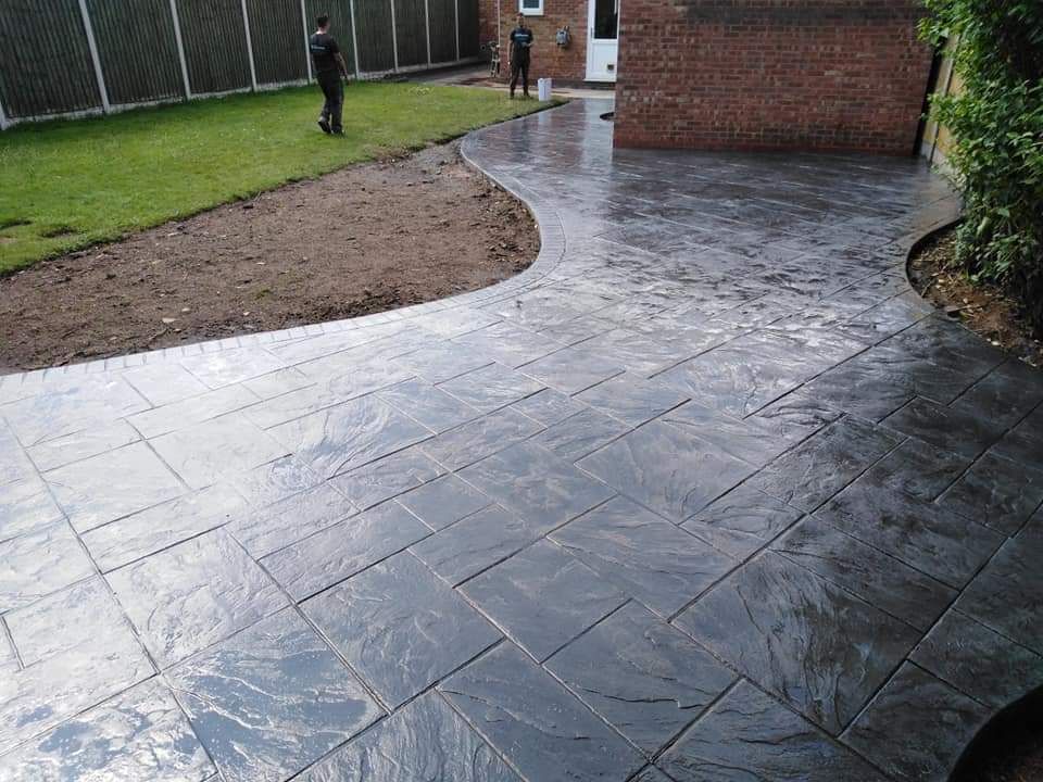 Slate effect imprinted concrete sweeping around the house with a curved border