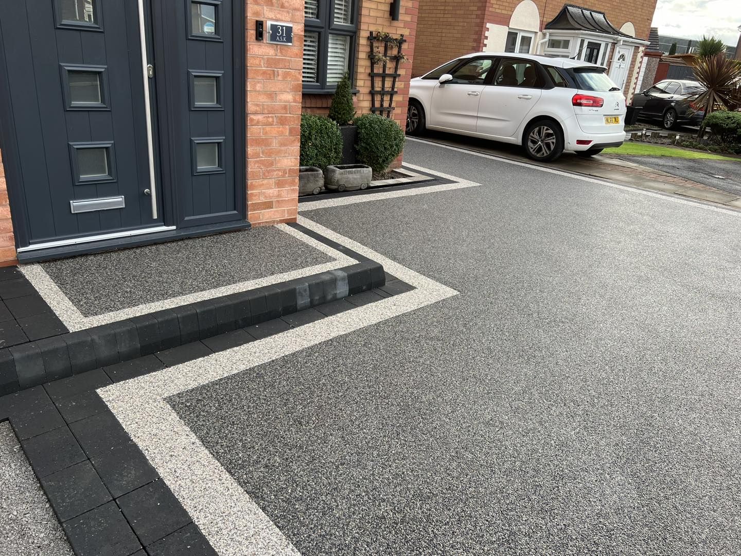 Grey resin bound driveway with cream banding wrapping the front entrance